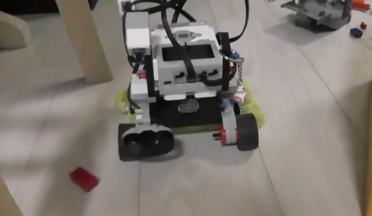 前方に赤外線センサが、後方にモップがついたEV3のロボットが、床を走行している。